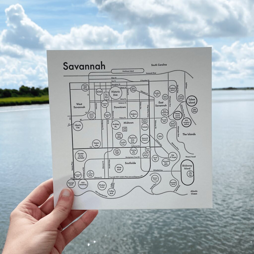 Map of Savannah created through a collaboration between Olive Ridley Studios and Archie's Press: Letterpress-printed map being held in front of a river