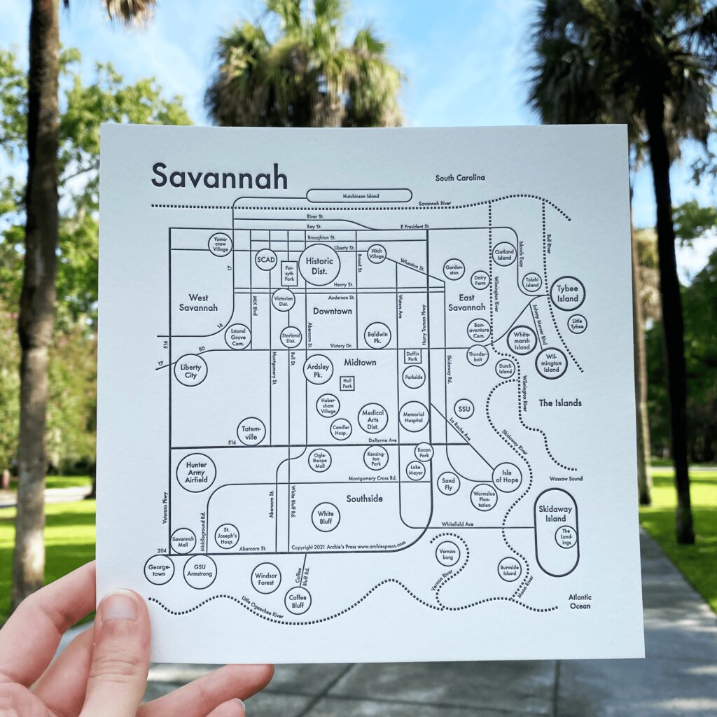 Map of Savannah created through a collaboration between Olive Ridley Studios and Archie's Press: Letterpress-printed map being held in front of a palm-lined avenue