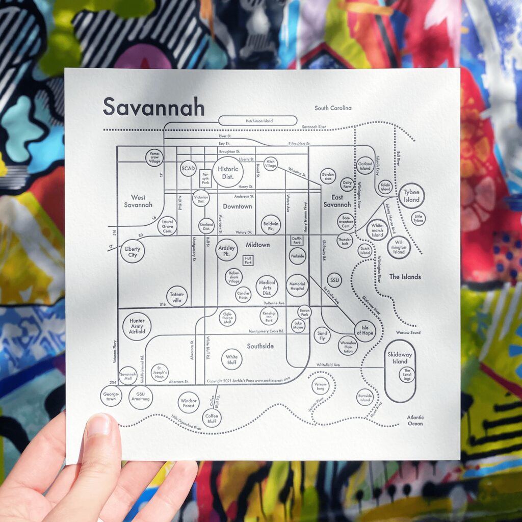 Map of Savannah created through a collaboration between Olive Ridley Studios and Archie's Press: Letterpress-printed map being held in front of local street art