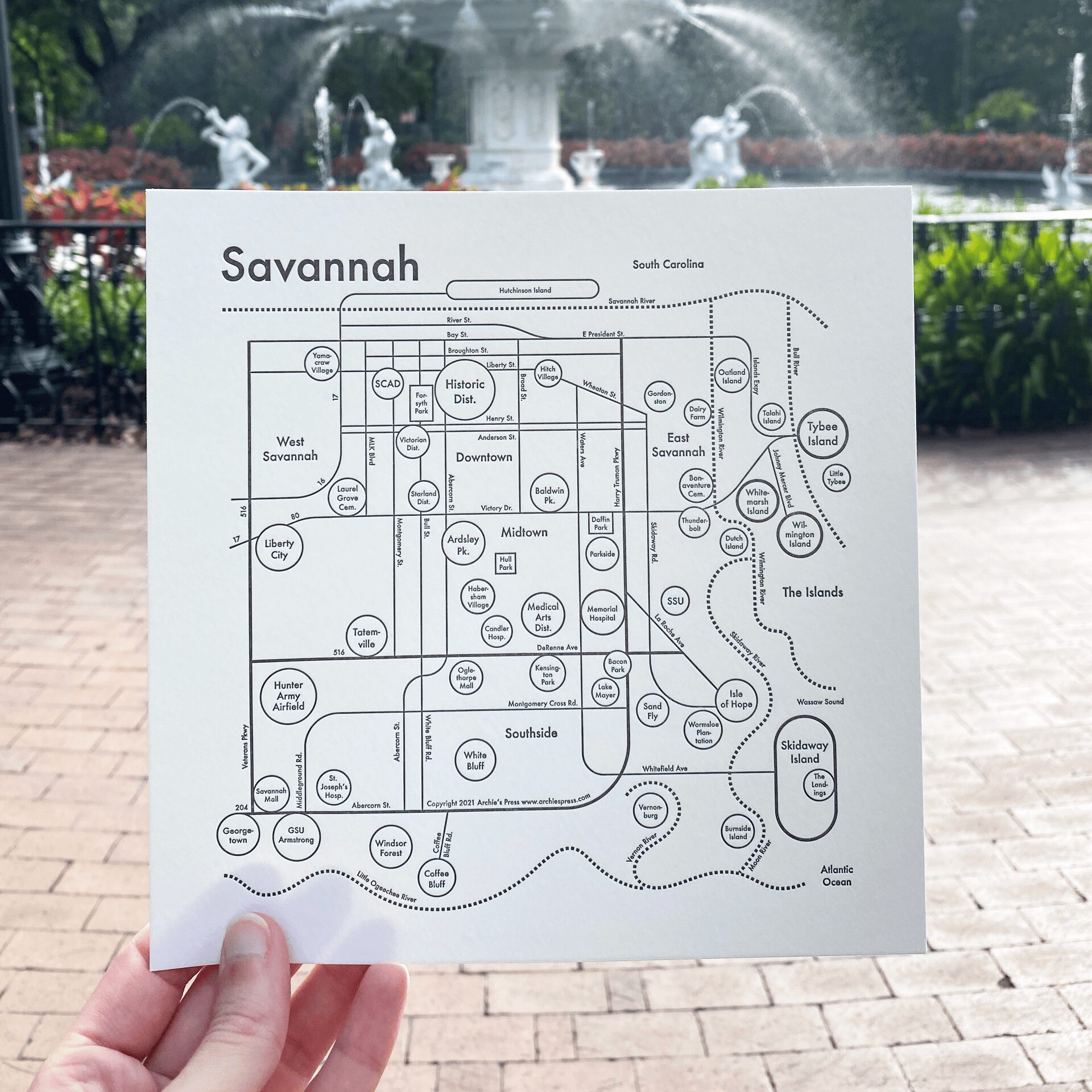 Map of Savannah created through a collaboration between Olive Ridley Studios and Archie's Press: Letterpress-printed map being held in front of Forsyth Park Fountain